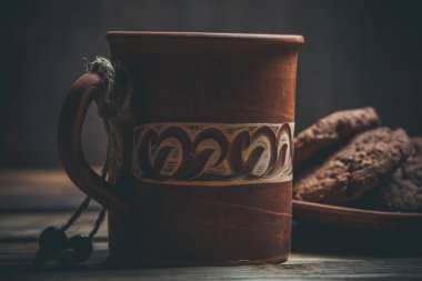 Kahverengi kil kahve fincanları ve ahşap bir masada sıcak renklerde lezzetli çikolatalı kurabiyeler.