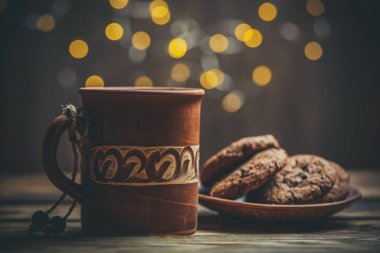 Kahverengi kil kahve fincanları ve ahşap bir masada sıcak renklerde lezzetli çikolatalı kurabiyeler.