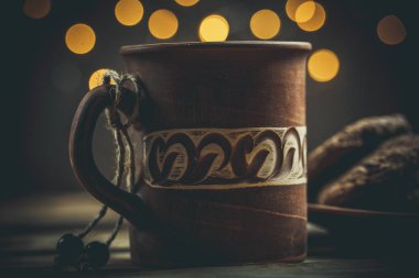 Kahverengi kil kahve fincanları ve ahşap bir masada sıcak renklerde lezzetli çikolatalı kurabiyeler.