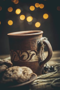 Kahverengi kil kahve fincanları ve ahşap bir masada sıcak renklerde lezzetli çikolatalı kurabiyeler.