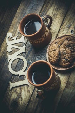 Kahverengi kil kahve fincanları ve ahşap bir masada sıcak renklerde lezzetli çikolatalı kurabiyeler.