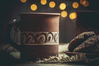 Kahverengi kil kahve fincanları ve ahşap bir masada sıcak renklerde lezzetli çikolatalı kurabiyeler.