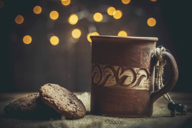 Kahverengi kil kahve fincanları ve ahşap bir masada sıcak renklerde lezzetli çikolatalı kurabiyeler.