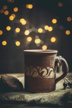 Kahverengi kil kahve fincanları ve ahşap bir masada sıcak renklerde lezzetli çikolatalı kurabiyeler.