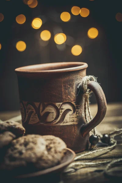 Kahverengi kil kahve fincanları ve ahşap bir masada sıcak renklerde lezzetli çikolatalı kurabiyeler.