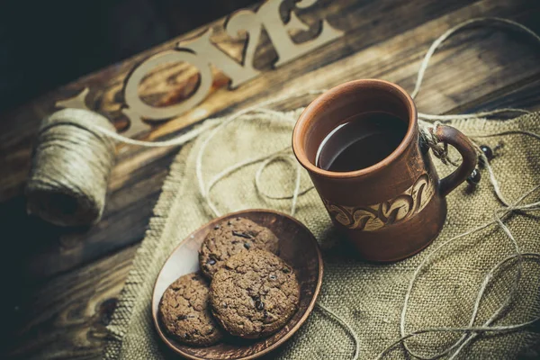 Kahverengi kil kahve fincanları ve ahşap bir masada sıcak renklerde lezzetli çikolatalı kurabiyeler.