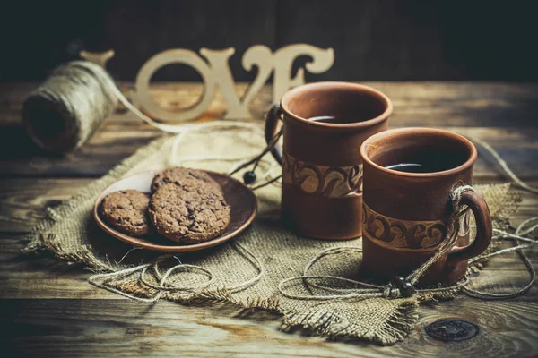Kahverengi kil kahve fincanları ve ahşap bir masada sıcak renklerde lezzetli çikolatalı kurabiyeler.
