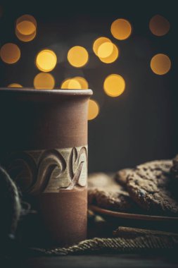 Kahverengi kil kahve fincanları ve ahşap bir masada sıcak renklerde lezzetli çikolatalı kurabiyeler.