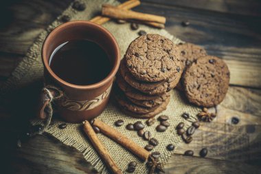 Kahverengi kil kahve fincanları ve ahşap bir masada sıcak renklerde lezzetli çikolatalı kurabiyeler.