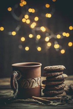 Kahverengi kil kahve fincanları ve ahşap bir masada sıcak renklerde lezzetli çikolatalı kurabiyeler.