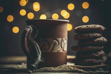 Kahverengi kil kahve fincanları ve ahşap bir masada sıcak renklerde lezzetli çikolatalı kurabiyeler.