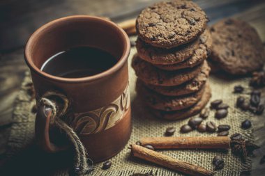 Kahverengi kil kahve fincanları ve ahşap bir masada sıcak renklerde lezzetli çikolatalı kurabiyeler.