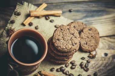 Kahverengi kil kahve fincanları ve ahşap bir masada sıcak renklerde lezzetli çikolatalı kurabiyeler.