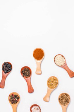 Beyaz arka planda tahta kaşıklardaki baharatlar ve malzemeler