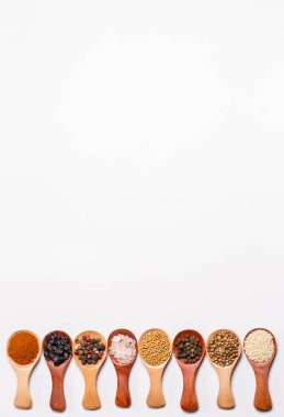 Beyaz arka planda tahta kaşıklardaki baharatlar ve malzemeler