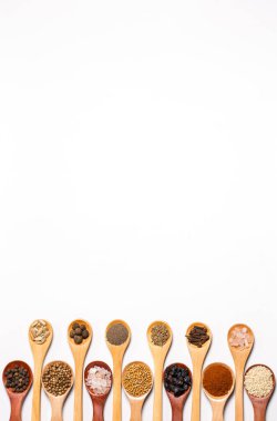 Beyaz arka planda tahta kaşıklardaki baharatlar ve malzemeler