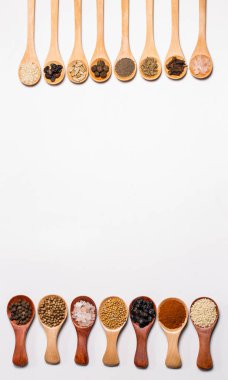 Beyaz arka planda tahta kaşıklardaki baharatlar ve malzemeler