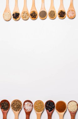 Beyaz arka planda tahta kaşıklardaki baharatlar ve malzemeler