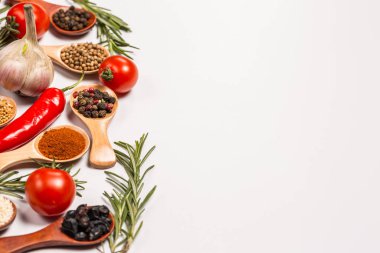 Tahta kaşıklardaki farklı baharatlar, farklı sebzeler, acı biber, kişniş, sarımsak, beyaz arka planda pişirmek için defne yaprağı.