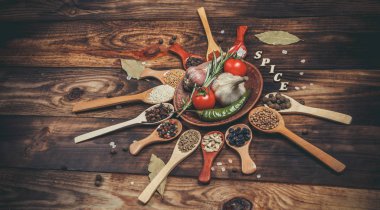 Ahşap kaşıklardaki farklı baharatlar ve pişirmek için farklı malzemeler, kiraz domatesleri, sarımsak, kişniş ve kırmızı biber.