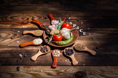 Ahşap kaşıklardaki farklı baharatlar ve pişirmek için farklı malzemeler, kiraz domatesleri, sarımsak, kişniş ve kırmızı biber.