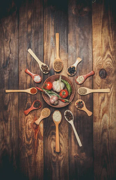 Ahşap kaşıklardaki farklı baharatlar ve pişirmek için farklı malzemeler, kiraz domatesleri, sarımsak, kişniş ve kırmızı biber.
