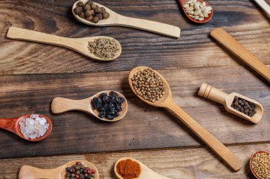 Ahşap bir masada, ahşap kaşıklardaki farklı baharatlar ve malzemeler.