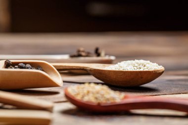 Ahşap bir masada, ahşap kaşıklardaki farklı baharatlar ve malzemeler.