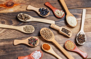 Ahşap bir masada, ahşap kaşıklardaki farklı baharatlar ve malzemeler.