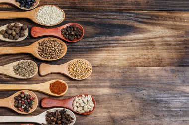 Ahşap bir masada, ahşap kaşıklardaki farklı baharatlar ve malzemeler.