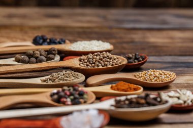 Ahşap bir masada, ahşap kaşıklardaki farklı baharatlar ve malzemeler.