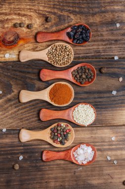 Ahşap bir masada, ahşap kaşıklardaki farklı baharatlar ve malzemeler.