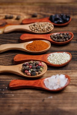 Ahşap bir masada, ahşap kaşıklardaki farklı baharatlar ve malzemeler.