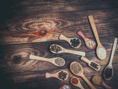 Ahşap bir masada, ahşap kaşıklardaki farklı baharatlar ve malzemeler.