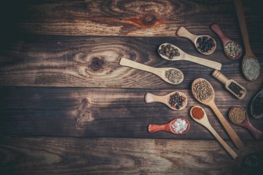Ahşap bir masada, ahşap kaşıklardaki farklı baharatlar ve malzemeler.
