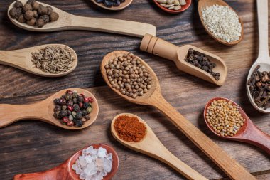 Ahşap bir masada, ahşap kaşıklardaki farklı baharatlar ve malzemeler.