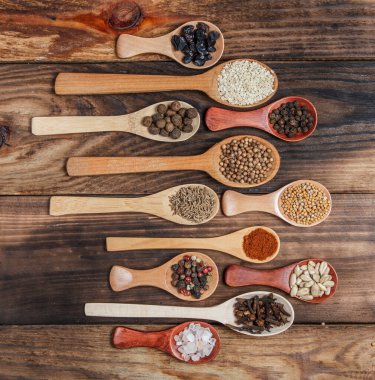 Ahşap bir masada, ahşap kaşıklardaki farklı baharatlar ve malzemeler.