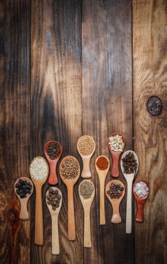 Ahşap bir masada, ahşap kaşıklardaki farklı baharatlar ve malzemeler.