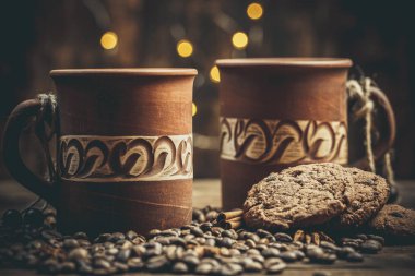 Kahve bardakları ve fincanlar, kahve taneleri ve zencefilli kurabiyeler sıcak ev renklerinde içecekler için yakınlarda.