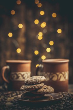 Kahve bardakları ve fincanlar, kahve taneleri ve zencefilli kurabiyeler sıcak ev renklerinde içecekler için yakınlarda.