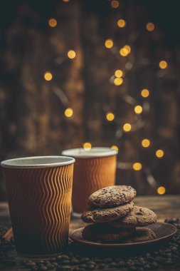 Kahve bardakları ve fincanlar, kahve taneleri ve zencefilli kurabiyeler sıcak ev renklerinde içecekler için yakınlarda.