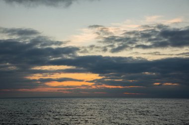 Kışın deniz kenarında koyu turuncu renklerde güzel bir gün batımı.
