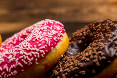 Tahta bir kahvaltı masasında çikolata ve pembe taze çörekler.