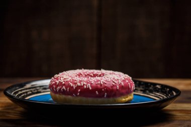 Ahşap bir tabakta lezzetli pembe donut.