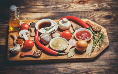 Ahşap bir arka planda yemek pişirmek için bir sürü farklı baharat, sebze ve malzeme.