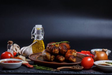 Izgara sosis, sebze, acı biber ve siyah arka planda çeşitli baharatlar.