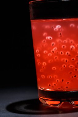 Siyah arka planda tanecikli lezzetli kırmızı kokteyl.