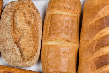 Beyaz zemin üzerinde buğday ve un bulunan lezzetli siyah beyaz ekmek.