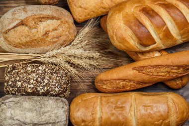 Tahta bir masada farklı somun ekmeği, buğday, un ve glüten.