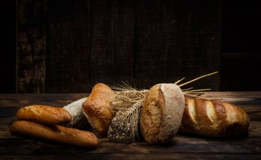 Tahta bir masada farklı somun ekmeği, buğday, un ve glüten.